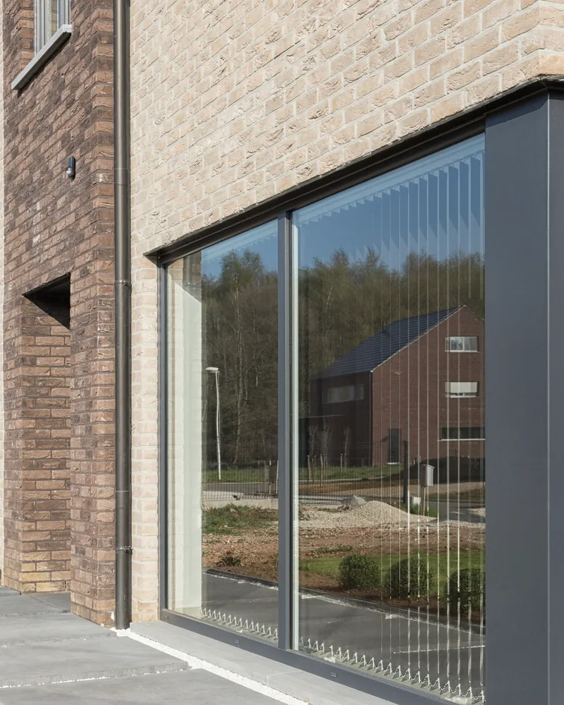 Grande baie vitrée en aluminium gris anthracite dans une façade en brique claire