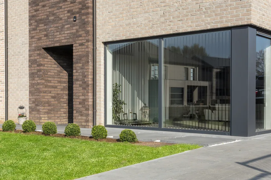 Angle vitré en aluminium anthracite dans une façade en brique