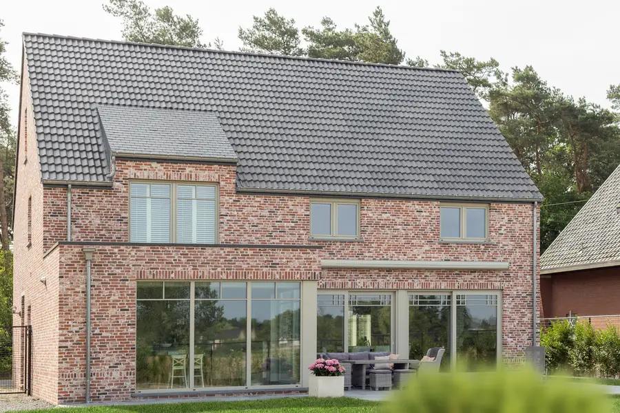 Arrière de maison en brique avec grandes baies vitrées sur terrasse