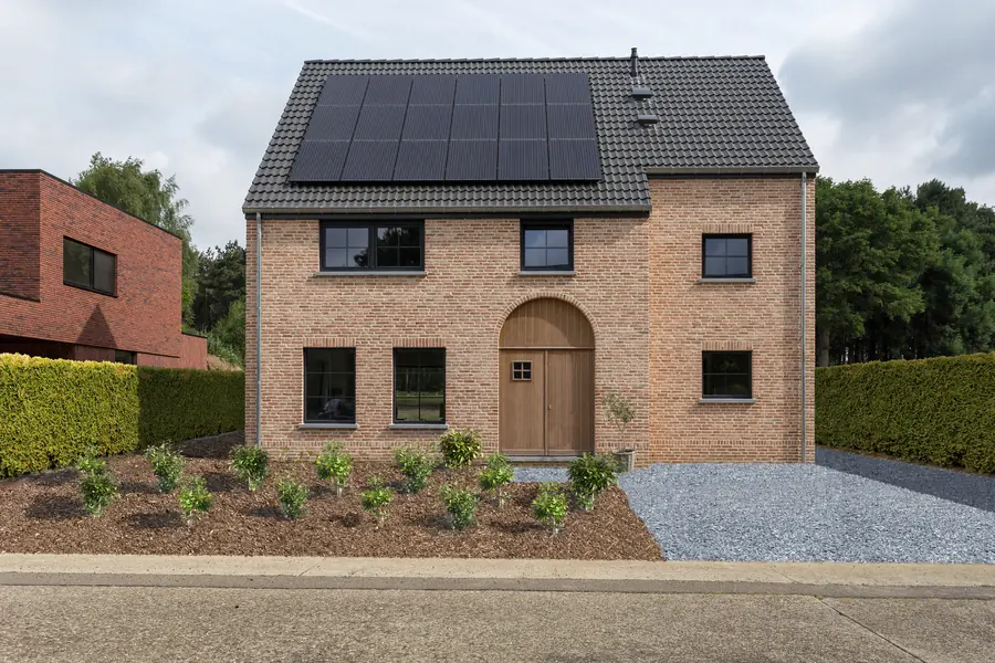 Maison en brique claire avec porte cintrée en bois et menuiseries noires